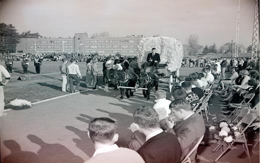 The Northwest 1962 Homecoming Queen arrives in a pomped, horse-drawn carriage for the start of the Homecoming Football Game.